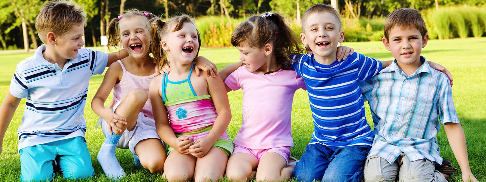 Children sitting on grass and smiling